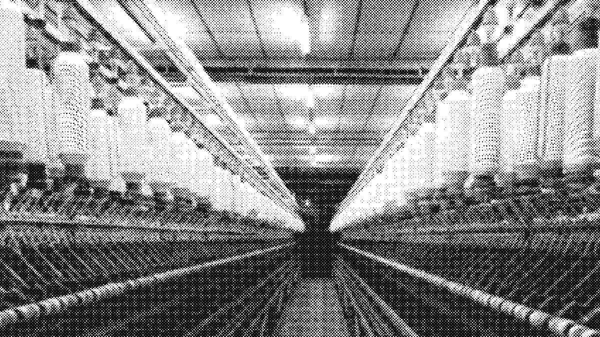 Corredor de uma fiação entre duas fileiras de máquinas iguais, que se estreitam até sumir num ponto de fuga ao fundo